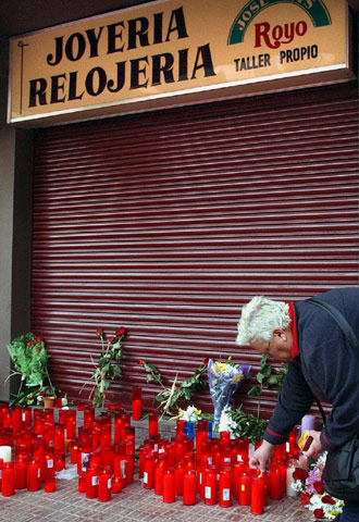 Una mujer deposita una vela ante la joyería del matrimonio asesinado.