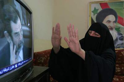 Una mujer chií, con una foto del ayatolá Alí Sistani a su espalda, durante la retransmisión del juicio a Sadam.
