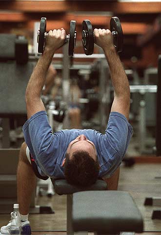 Un joven hace ejercicios con pesas en un gimnasio.