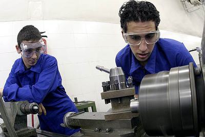 Dos alumnos de garantía social trabajan con piezas mecánicas.