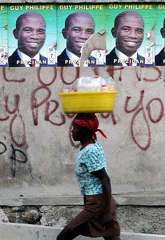 Una mujer pasa frente a carteles electorales en Puerto Príncipe.