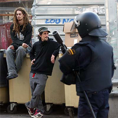 Dos  okupas , frente a un policía antidisturbios que participó en el desalojo de ayer.