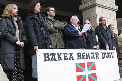 El alcalde de Mungia, José Antonio Torrontegui (PNV), lee un comunicado de condena del atentado, detrás de una pancarta con el lema, en euskera,  Necesitamos la paz .