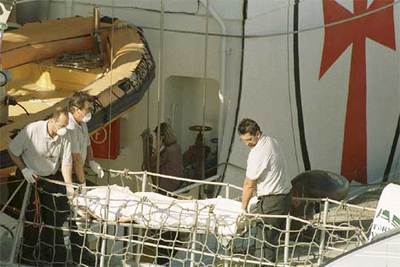 Tres personas desembarcan uno de los 25 cadáveres rescatados por el buque hospital  Esperanza del Mar  en aguas cercanas a Mauritania.