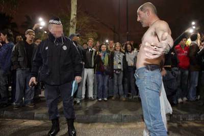 Un participante en el  botellón  de la Rambla del Raval (Barcelona) discute con un agente.