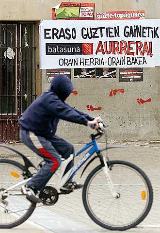 Un joven ciclista pasa delante de unos carteles de Batasuna, en Pamplona.