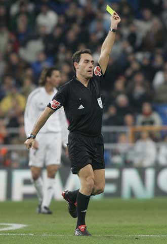 Un árbitro, Pérez Burrull, enseña una tarjeta durante un partido.