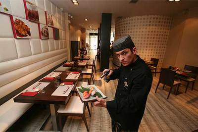 El  chef  Alex Moranda, en el restaurante 19 Sushi Bar, en Madrid. Abajo, tarta de ventresca con salsa picante.