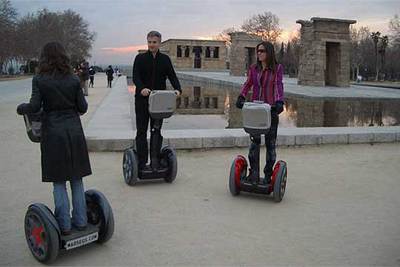 Un grupo de personas se desliza en Segway sobre la arena del parque que rodea el templo de Debod, en Madrid.
