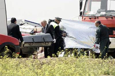 Empleados de la funeraria trasladan los cuerpos del instructor y la alumna fallecidos tras el choque.