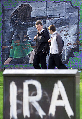 Dos estudiantes caminan entre varias pintadas del IRA en Belfast.