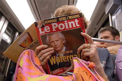 Una mujer lee un ejemplar de la revista  Le Point   con un retrato de  Villepin y el texto 