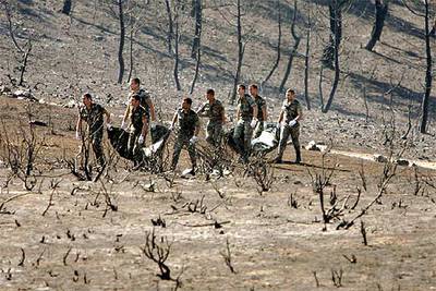 Varios soldados trasladan los cadáveres de dos de las víctimas del incendio el 19 de julio de 2005.