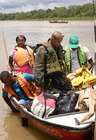 Un agente de la policía nacional de Colombia revisa los equipajes de unos pasajeros que navegan por el Atrato.