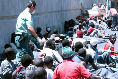 Los inmigrantes llegados en una patera a La Gomera esperan sentados a pasar el reconocimiento médico.