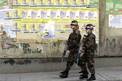 Dos soldados pasan por delante de un muro con carteles de los candidatos presidenciales en Bogotá.