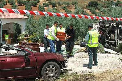 Cuatro operarios trasladan los cuerpos de los fallecidos en un accidente en Cabra (Córdoba).