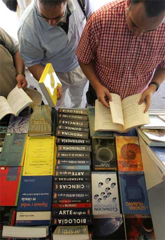 Dos lectores hojean ayer libros en una de las casetas de la Feria del Libro en el Retiro.