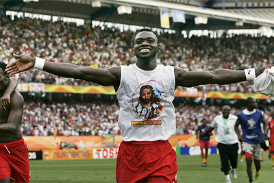 John Mensah, con una imagen de Jesucristo en la camiseta, celebra  la clasificación para octavos.