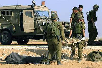 Soldados israelíes retiran los cuerpos de sus camaradas muertos en el ataque de los milicianos palestinos en la frontera sur de la franja de Gaza.