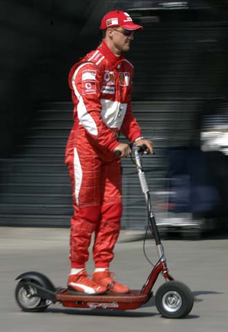 Michael Schumacher pasea por el  paddock  en un patinete eléctrico.