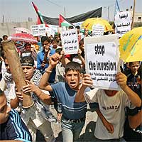 Niños palestinos piden con un cartel el 'fin de la invasión' israelí durante una manifestación en Rafah, al sur de la franja de Gaza, ayer.