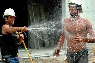 Dos obreros de la construcción se refrescan para combatir el calor.