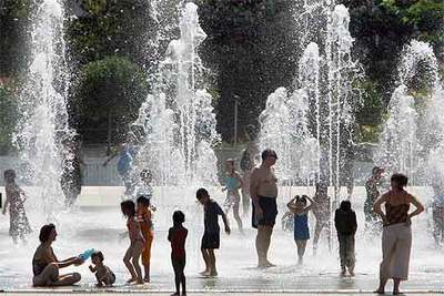 Gente refrescándose en una fuente del parque André Citroën, en París.
