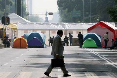 Un hombre cruza el paseo de la Reforma observando las tiendas de campaña de los perredistas.