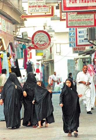 Dos saudíes, con la   abaya   y el   burka  , y dos niñas, sólo con la   abaya  , caminan por el mercado de Dammam (Arabia Saudí).
