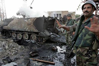 Soldados libaneses junto a un blindado destruido ayer por los ataques de la aviación israelí en la ciudad portuaria de Tirorn.