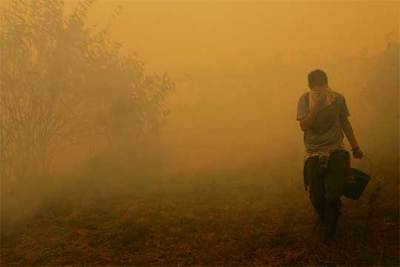 El humo obliga a un vecino de Cotobade (Pontevedra) a protegerse la cara con un pañuelo.