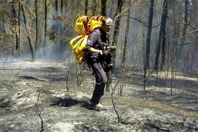 Un miembro del servicio de extinción de incendios lleva una manguera en medio del bosque quemado en Palau de Santa Eulàlia (Girona).