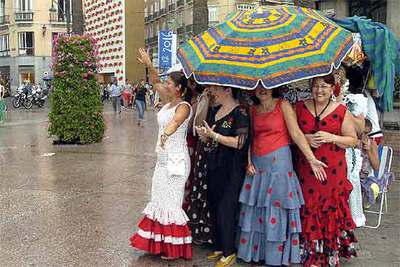 Un grupo de mujeres se resguarda de la lluvia en la Feria de Agosto de Málaga.