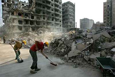 Partidarios de Hezbolá barren una calle en un área residencial destruida al sur de Beirut.