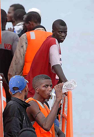 Un grupo de inmigrantes interceptados en una embarcación se refresca en el puerto de los Cristianos.