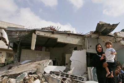 Una mujer palestina de Gaza y sus hijos, delante de las ruinas de su casa, destruida por el Ejército israelí.