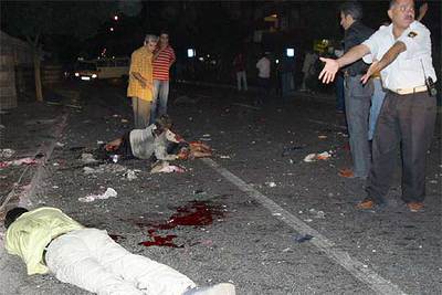 Un policía gesticula ante de un cadáver mientras una mujer herida espera ayuda anoche en Diyarbakir.