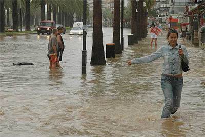 Varias personas cruzan por una calle de Salou que ayer por la tarde permanecía inundada.