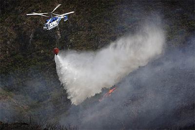 Un helicóptero descarga agua sobre el incendio de la Serra de l'Almirant.