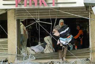 Dos mujeres libanesas sacan la mercancía de una tienda de ropa destruida por las bombas de la aviación israelí.