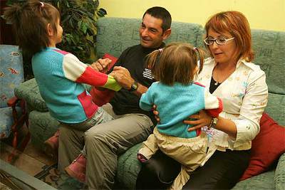 Paula, en las rodillas de su madre, con su padre y su hermana en su casa de Utiel.