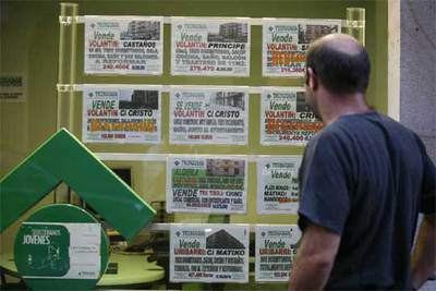 Un hombre revisa varios carteles de pisos en venta y alquiler en una agencia inmobiliaria de Bilbao.