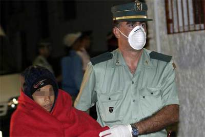 Un guardia civil acompaña a uno de los menores llegados en patera a las costas de Granada el pasado lunes.