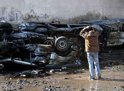 Un iraquí contempla un amasijo de coches destruidos por la explosión de una bomba ayer en Bagdad.