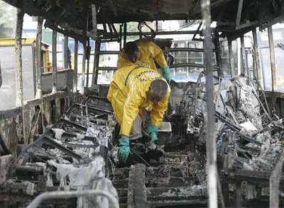 Dos personas inspeccionan uno de los autobuses incendiados.