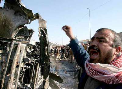 Un iraquí grita ante los restos del minibús bomba que explosionó ayer en el centro de Kufa, una ciudad a 160 kilómetros al sur de Bagdad.