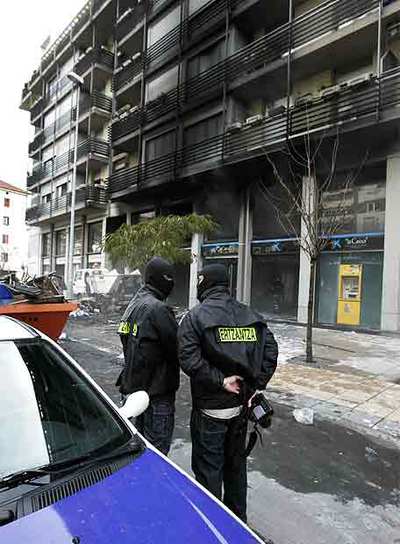 Dos  ertzainas  vigilan el edificio atacado en Mondragón.