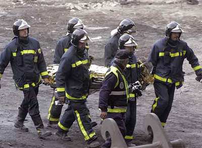 Los bomberos trasladan el cadáver de Diego Armando Estacio tras recuperarlo de los escombros.