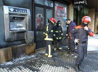 Agentes de la Ertzaintza y bomberos examinan los daños causados por el ataque a un cajero en San Sebastián . 